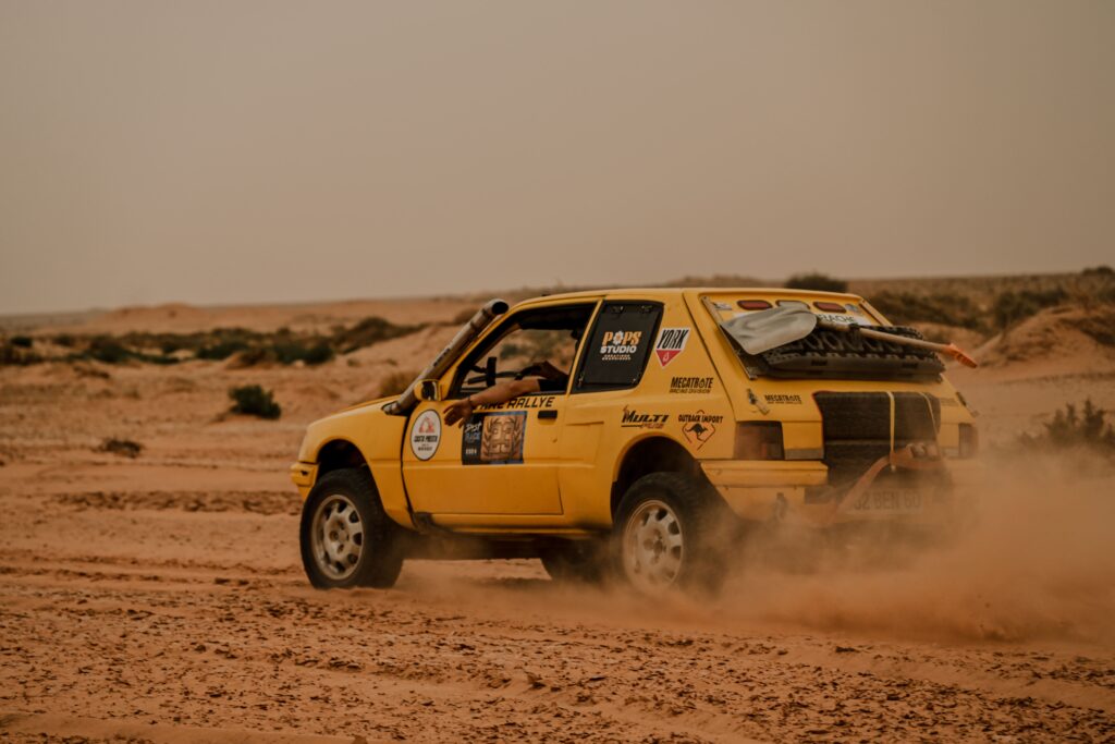205 préparée Mecatrote soulevant la poussière sur piste désertique – Provence Overland Festival Marignane