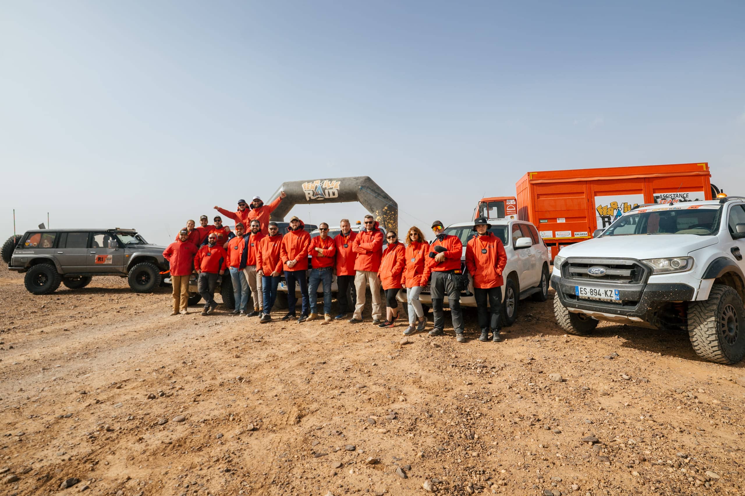 Équipe Mecatrote en vestes rouges devant arche de départ raid – Provence Overland Festival Marignane 2026